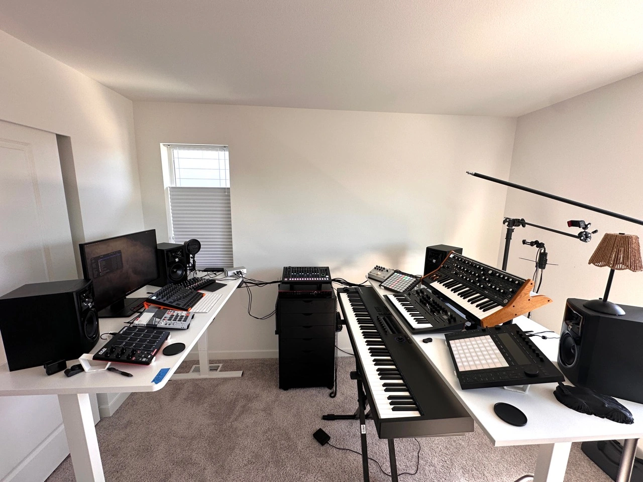 Gus Vega's actual studio: two equipment desks, an 88-key keyboard, stacked synthesizers, pad controllers, audio equipment, four monitors and microphones.